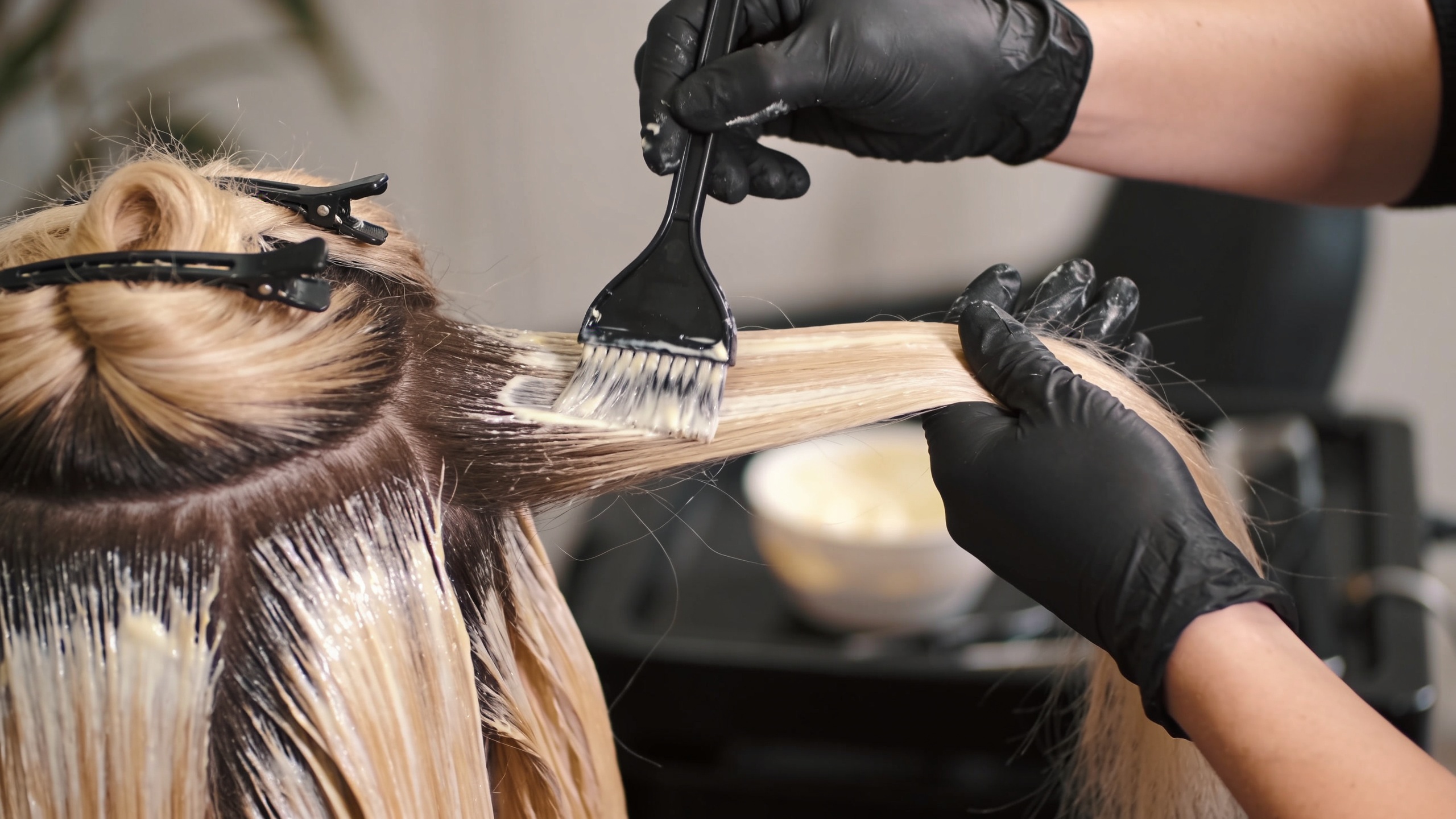plan serre cinematique sur les mains expertes d un coiffeur appliquant un balayage lumineux avec pinceau professionnel et separation nette des meches
