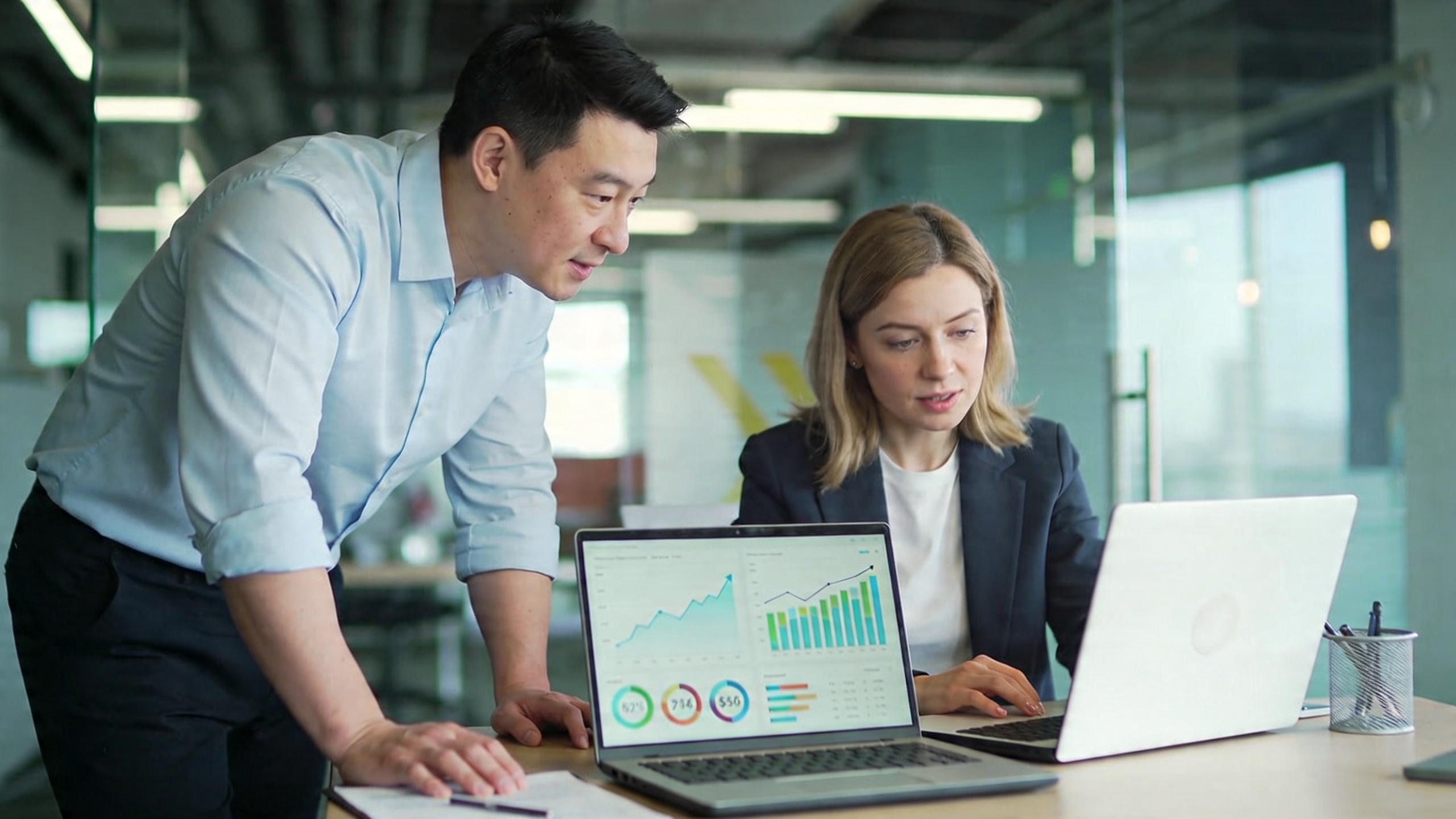 Coach homme et femme collaborant sur un ordinateur portable affichant des outils d'analyse de données marketing, avec des graphiques de croissance et des chiffres positifs, ambiance de travail dynamique et moderne, style photo éditorial