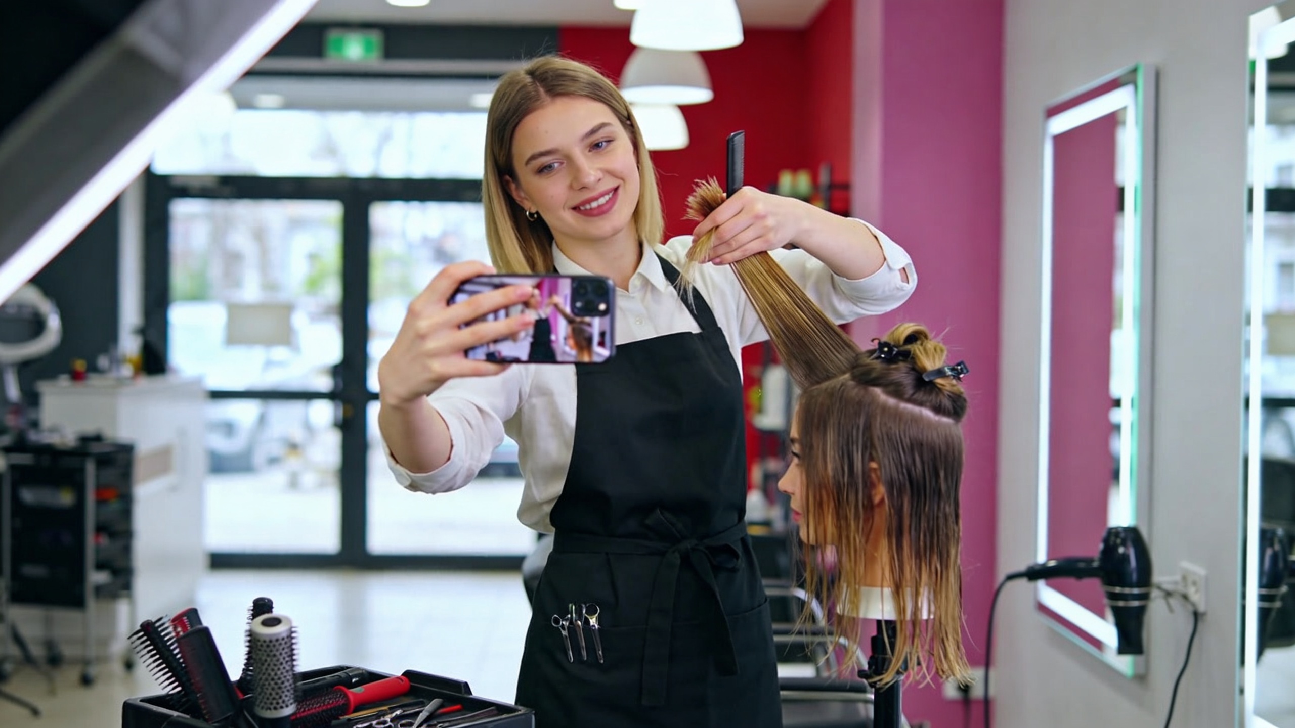Jeune femme coiffeuse créant un Reel Instagram captivant avec des outils professionnels, un smartphone en main, dans un décor de salon de coiffure moderne. La scène est dynamique et pleine d'énergie, style photo éditorial.